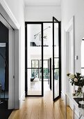 Hallway with open, black glass double door and a view of the living area and gallery