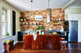 Küche mit Backsteinwand, Kücheninsel und Holzboden