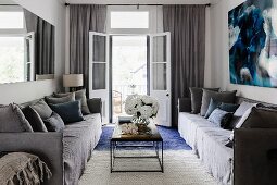 Cozy, gray sofa set and coffee table with metal base in front of an open balcony door