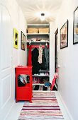 Cloakroom with shelving and coat pegs in niche, rag rug and red console cabinet