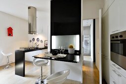 White bar stools in front of black partition with fold-up, glossy table top