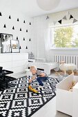 Little boy playing on rug in monochrome child's bedroom