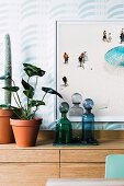 Ivy and cactus next to glass flacons in front of a beach picture