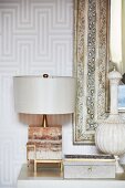 Table lamp, jewellery box and vase in front of mirror with antique frame