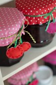 Mit genähten Kirschanhängern und gepunkteten Stoffen dekorierte Marmeladengläser