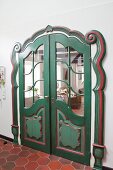 Artistically decorated double doors painted green and red in renovated farmhouse