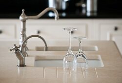 Washed wine glasses on Silestone kitchen worksurface next to sink with vintage tap fittings