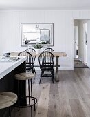 Rustic wooden table with black chairs in open kitchen with kitchen counter