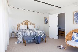 Doppelbett mit kunsthandwerklichem Betthaupt in reduziertem Schlafzimmer mit Tagesdecke und Kleiderbank