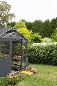 Anthracite greenhouse for succulents with a sliding door next to a green hedge