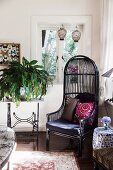 Elegant, black wicker chair in the corner of the living room next to a nostalgic sewing machine table with a green plant