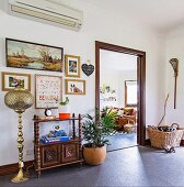 Anteroom with oriental floor lamp, shelf cabinet, pictures and house plants, view of the living room