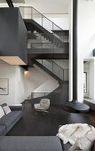 Staircase and suspended fireplace in double-height black-and-white interior