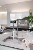 Kitchen island with an integrated sink, washing-up water and glasses