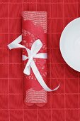 Red linen napkin and lace doily tied with white ribbon on red tablecloth