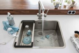 A white work surface with a built-in sink with a drainer and a tap