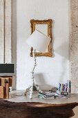 White standard lamp in front of gilt frame on white-painted brick wall