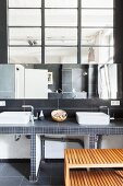 Twin countertop sinks in minimalist bathroom of loft apartment with industrial interior window