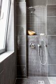 Grey-tiled shower area with mosaic tiles and wall-mounted fittings