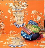 A bowl of colourful ethnic textiles on orange fabric