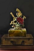 Totenkopf-Skulptur mit einer Blume auf altem Holzköfferchen