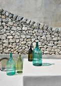 Arrangement of bottles in front of stone wall outside