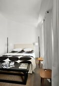 Black and white bed linen on double bed in bedroom with floor-length curtains
