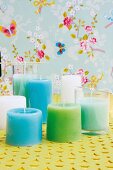 Pastellfarbene DIY-Kerzen in Gläser gegossen vor Blütentapete
