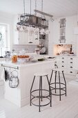 Island counter and bar stools in white country-house kitchen