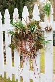 Spring wreath made of snowdrops, moss and willow catkins hung on white picket fence