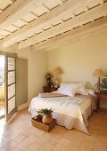 Wood-beamed ceiling and terracotta floor in Mediterranean bedroom