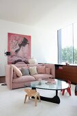 Children's chairs around glass coffee table and dusky-pink couch with scatter cushions in elegant lounge
