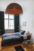 Schlafzimmer mit Doppelbett, Vintage-Nachttischlampe und Hängelampe mit Korbschirm in Altbauwohnung