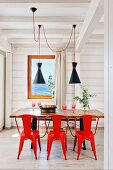 Rote Metallstühle am Holztisch im weißen Holzhaus