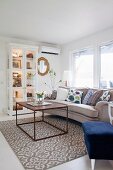 Cubic coffee table on patterned rug in front of sofa and display cabinet