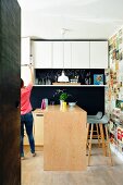 weiße Oberschränke und Küchentheke vor Wand mit Retro Zeitungsausschnitten tapeziert