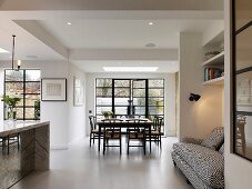 Open-plan interior with white floor, dining area and sofa in niche