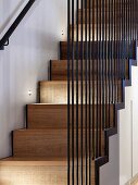 Modern wooden staircase with iron-rod balustrade and spotlights