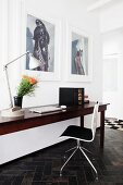 Edelholztisch mit Laptop und Designerstuhl vor grossformatigen Fotos