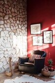 Black leather armchair and carved wooden snake in front of stone wall abutting red wall