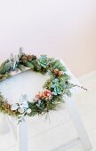 Wreath of twigs and succulents on white wooden stool