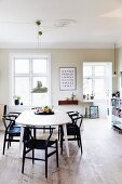 Black designer chairs around oval table in bright dining room