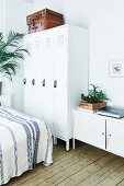 Leather suitcases on top of white lockers and sideboard in bedroom with rustic board floor