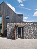 Modernes Haus mit Fassade aus dunklem Holz und Stein