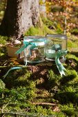 Painted wooden toadstools under upturned mason jars decorated with ribbons in woods