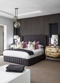Antique chest of drawers and artistic table lamps in elegant bedroom