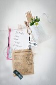 Hand-made wire utensils and shopping list clipped to cord with clothes pegs decorating kitchen wall