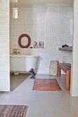 Free-standing vintage-style bathtub and white mosaic-tiled wall in bathroom