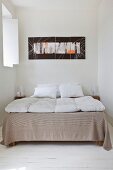 Double bed and modern artwork in bedroom with white board floor