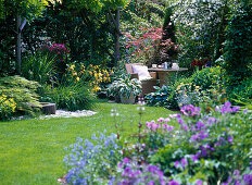 Gartenansicht mit Blick auf kleine Terrasse mit Sitzplatz, bewachsene Pergola